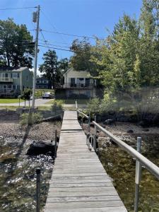 a wooden bridge over a river with houses in the background at LOON LODGE LIMIT 8 home in Standish