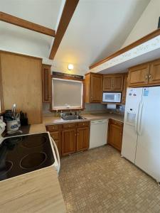 a kitchen with wooden cabinets and a white refrigerator at LOON LODGE LIMIT 8 home in Standish
