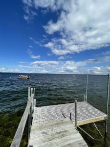 a dock on the water with a boat in the distance at LOON LODGE LIMIT 8 home in Standish