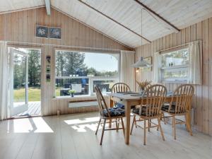a dining room with a table and chairs and windows at Holiday Home Akka - 2km from the sea by Interhome in Saltum