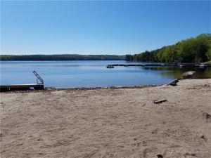 a beach with a bench and a dock in the water at ALPINE VILLAGE GETAWAY LIMIT 8 cottage in Bridgton