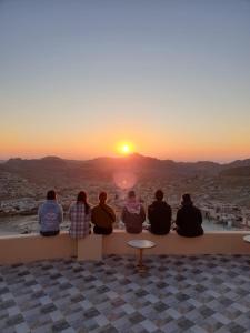 Un gruppo di persone sedute su un cornicione a guardare il tramonto di Cozy House a Wadi Musa