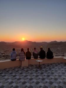 a group of people sitting on a ledge watching the sunset at Cozy House in Wadi Musa