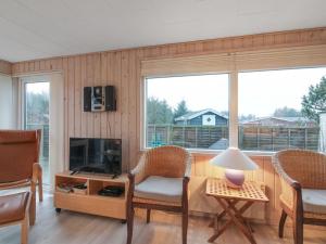 a living room with chairs and a television and a table at Holiday Home Liisi - 500m from the sea in NW Jutland by Interhome in Hjørring