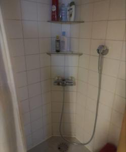 a shower in a white tiled bathroom with a hose at Veikkola Karstula in Karstula