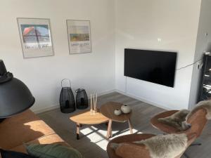 uma sala de estar com uma televisão, cadeiras e uma mesa em Apartment Almar - 400m from the sea in NW Jutland by Interhome em Hjørring