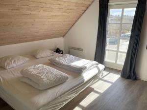 a bed with two pillows on it in a room with a window at Apartment Almar - 400m from the sea in NW Jutland by Interhome in Hjørring