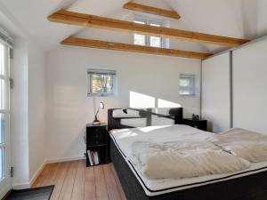 um quarto com uma cama grande, paredes brancas e pisos em madeira em Holiday Home Iara - 6km from the sea in NW Jutland by Interhome em Bindslev
