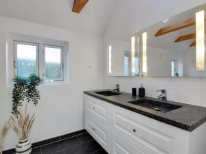 uma casa de banho branca com 2 lavatórios e um espelho em Holiday Home Iara - 6km from the sea in NW Jutland by Interhome em Bindslev