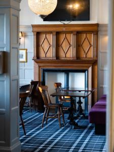 a room with a fireplace with a table and chairs at The Heworth Inn in York