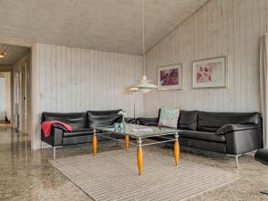 een woonkamer met een zwarte bank en een tafel bij Holiday Home Gilbert - 150m from the sea in NW Jutland by Interhome in Hjørring