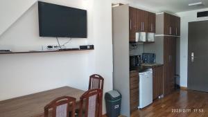 a kitchen with a table and a television on a wall at Apartman Studio Lux u Kraljevim Čardacima in Kopaonik