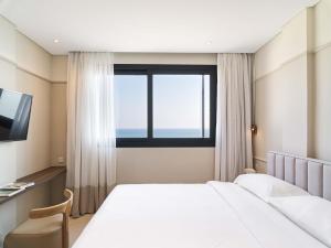 a hotel room with a large bed and a window at LIV Mackenzie Beach Suites Larnaca in Larnaca +154 photos