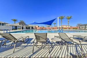 a group of chairs and blue umbrellas next to a swimming pool at Spacious Gilbert Vacation Rental with Patio! in Gilbert