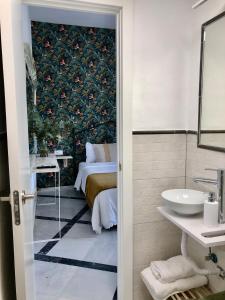 a bathroom with a bed and a sink and a mirror at Apartamentos Makao Puerta del Olivillo in Jerez de la Frontera