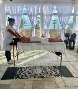 a woman is making a bed in a room at Pousada Tortugas in Guarujá