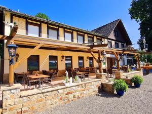 eine Terrasse mit Tischen und Stühlen vor einem Gebäude in der Unterkunft Hotel Waldquelle - Baumhaushotel Aerzen in Aerzen