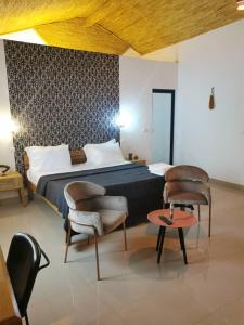 1 Schlafzimmer mit einem Bett, 2 Stühlen und einem Tisch in der Unterkunft La Fandenoise in Thiès