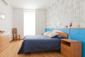 1 dormitorio con cama y pared azul en Hostal Montaloya, en Madrid