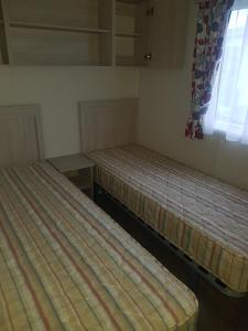 two empty beds in a room with a window at 6 Berth on John Fowlers (Sandy Glade) Brean in Berrow