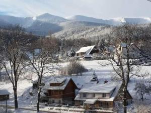 un pueblo cubierto de nieve con montañas en el fondo en Wysokie Bale Kwatery Jagniatków, en Jelenia Góra