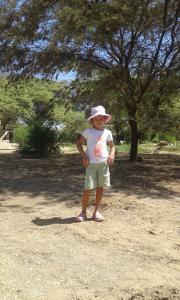 a little girl in a hat standing in a field at Camping Matufa Mancora in Canoas De Punta Sal