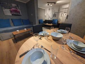 a dining room table with wine glasses and a couch at JDK Apartamenty Młynarska 44m2 6-osobowy in Kalisz
