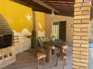 eine Terrasse mit einem Tisch, Stühlen und einer Ziegelwand in der Unterkunft Vila Japaraiso-Casa Amarela Próxima ao mar in Japaratinga