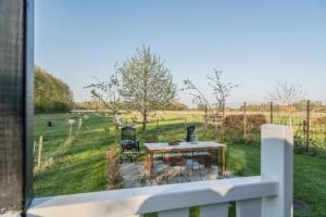 a balcony with a table and chairs in a field at boerderijkamer Zwanebloem in Onstwedde