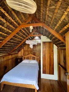 a bed in a room with a wooden ceiling at Zutalu - Playa Sur in Puerto López