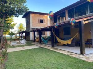 a house with a hammock outside of it at Vila Japaraiso-Casa Amarela Próxima ao mar in Japaratinga