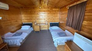 Habitación con 2 camas en una cabaña de madera en OXUS ADVENTURE YURT CAMP en Nurota
