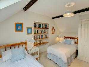a bedroom with two beds and a book shelf at Brook Cottage in Newton Ferrers