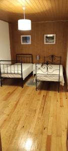 a room with two beds and a wooden floor at Quinta do Torgal - Alojamento Local in Unhais da Serra