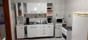 a small kitchen with white cabinets and a refrigerator at Praça Residence in Uruguaiana