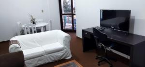 a living room with a desk and a tv and a chair at Praça Residence in Uruguaiana