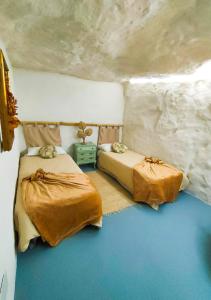 een slaapkamer met 2 bedden in een stenen kamer bij La Cueva Blanca in Alcalá del Júcar
