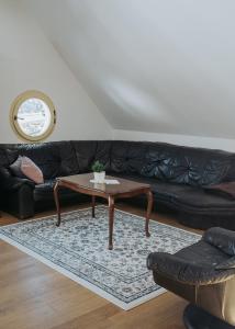a living room with a black couch and a coffee table at Apartments Možinetova hiša in Šentjošt nad Horjulom