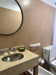 y baño con lavabo, espejo y aseo. en ALOHA Güemes Premium, 1 dorm Clásico y Moderno en Córdoba