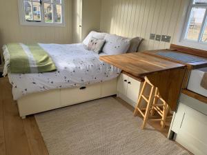 a small bedroom with a bed and a desk at Weatherhead Farm Shepherds Hut in Buckingham