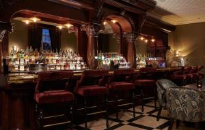 a bar with red chairs and a lot of alcohol at Aldwark Manor Estate in Aldwark