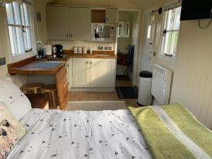a small kitchen with a bed in a tiny house at Weatherhead Farm Shepherds Hut in Buckingham