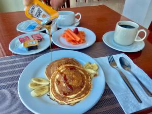 un tavolo con piatti di pancake, carote e caffè di Hotel Enterprise Inn Poliforum a León