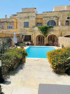 a swimming pool in front of a building at Ta' Klementa Farmhouse in Għarb