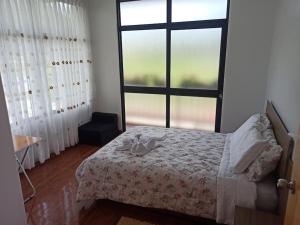 a bedroom with a bed and a large window at Hermosa y espléndida casa en Oxapampa in Oxapampa