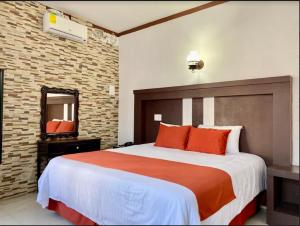 a bedroom with a large bed with orange pillows and a mirror at Pineda Real HOTEL in Tonalá