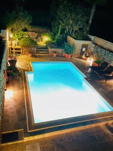 a swimming pool with lights in a backyard at night at Ta' Klementa Farmhouse in Għarb