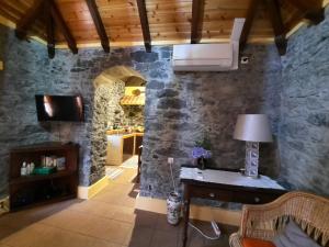 a living room with a stone wall and a kitchen at Casa Rosa in Camacha