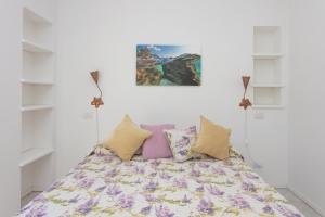 - une chambre avec un lit doté d'oreillers violets et jaunes dans l'établissement Le Gemme Guest House, à Anacapri