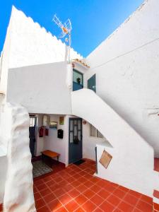 een wit huis met een trap en een rode tegelvloer bij La Cueva Blanca in Alcalá del Júcar